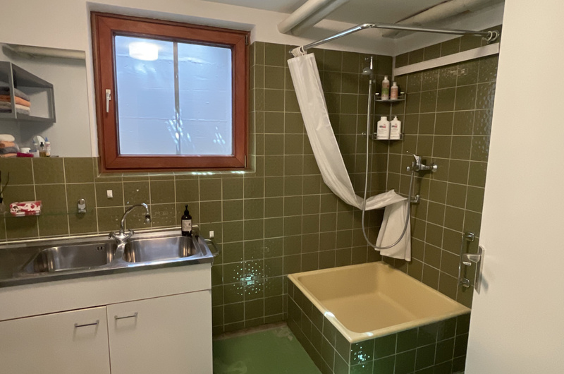 Links alter Duschbereich mit Kniehoher Duschtasse und moosgrünen Fliesen - rechts: bodenebene Dusche mit grauen Boden- und hellblauen Wandfliesen